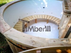 TimberIN Nordic Flex – vista obliqua dall'alto della vasca interna bianca con panca curva in legno, protezione della stufa e fori per i getti