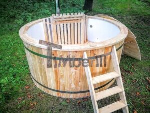 TimberIN Nordic Flex aperta in un giardino boscoso, vista dall'alto, con vasca interna chiara, scaletta in legno e griglia di protezione della stufa interna