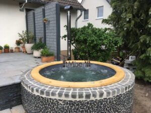 TimberIN Nordic InGround Comfort incassata con bordo in ghiaia, circondata da piante e alberi