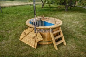 TimberIN Nordic Flex aperta su un prato, con vasca interna blu, scaletta a destra e due parti del coperchio in legno appoggiate a sinistra