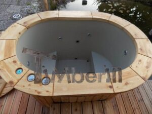 Vasca ovale TimberIN Nordic Oval Duo per due persone su una terrazza in legno vicino all'acqua