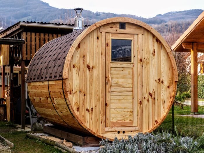 Sauna a botte in abete con porta a vetri in un giardino