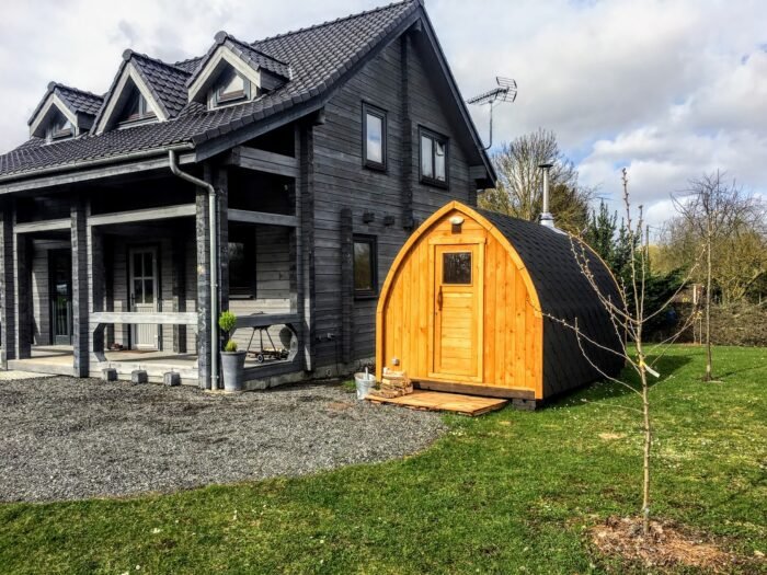 Sauna a igloo in legno nel giardino accanto a una casa