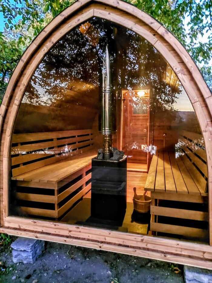 Stufa a legna al centro di una sauna a igloo con parete in vetro