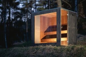 Sauna moderna da esterno TimberIN Nordic Cube con vetrata illuminata, vista frontale