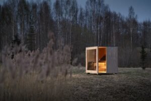Sauna da esterno TimberIN Nordic Cube di sera nel bosco