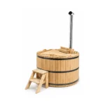 TimberIN Nordic™ Wooden Basic – vasca rotonda in legno massello di abete chiaro con panche curve, stufa interna protetta, camino, scaletta in legno e coperchio in legno su sfondo bianco.