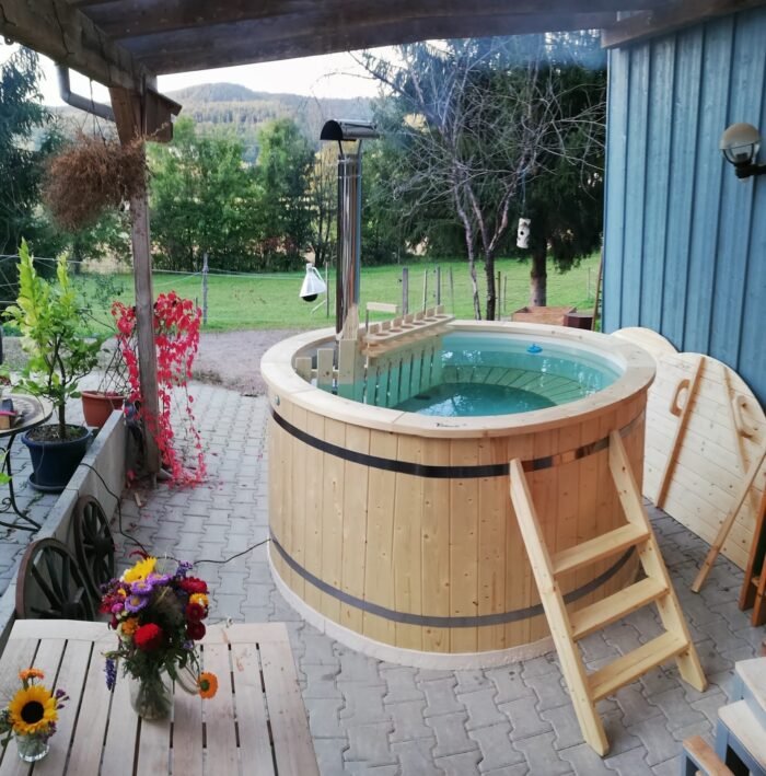 Tinozza in legno sotto una pergola tra vasi di fiori, con vista sulla campagna